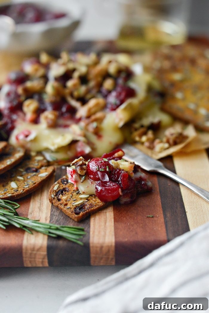 Golden Maple-Drizzled Brie with Ruby Cranberry Swirl 16 Maple Baked Brie with Cranberry Jam on a wooden board with accompaniments