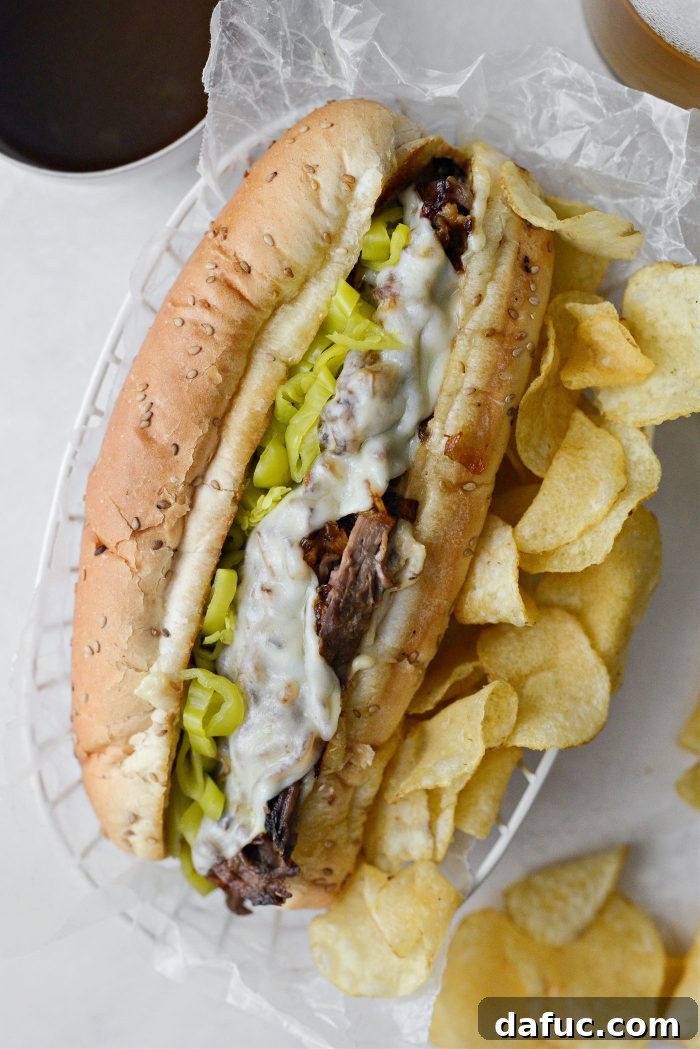Mississippi Pot Roast Sandwich - A succulent, shredded pot roast sandwich on a toasted bun with melted provolone, crispy onions, and pepperoncini, served with au jus.