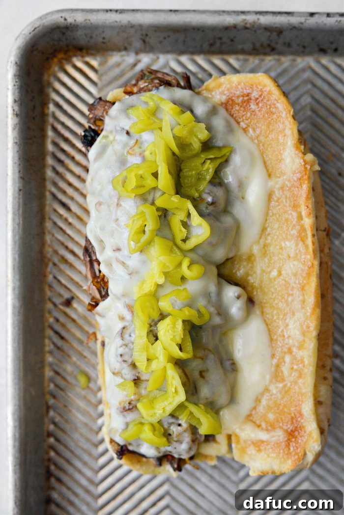 Finishing the Mississippi Pot Roast Sandwich with a generous topping of sliced pepperoncini peppers.