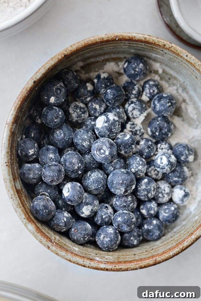 Blueberries tossed with a small amount of dry ingredients in a bowl