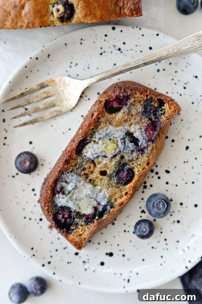 Close-up of a slice of Blueberry Banana Bread with melted butter