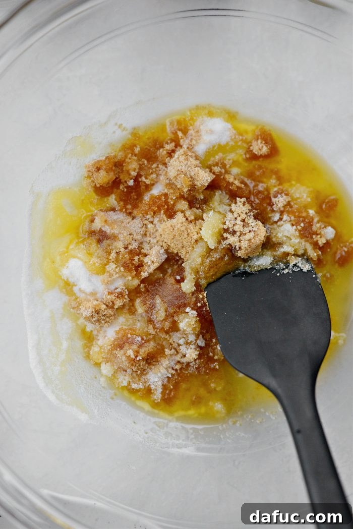 Melted butter and two types of sugar in a mixing bowl