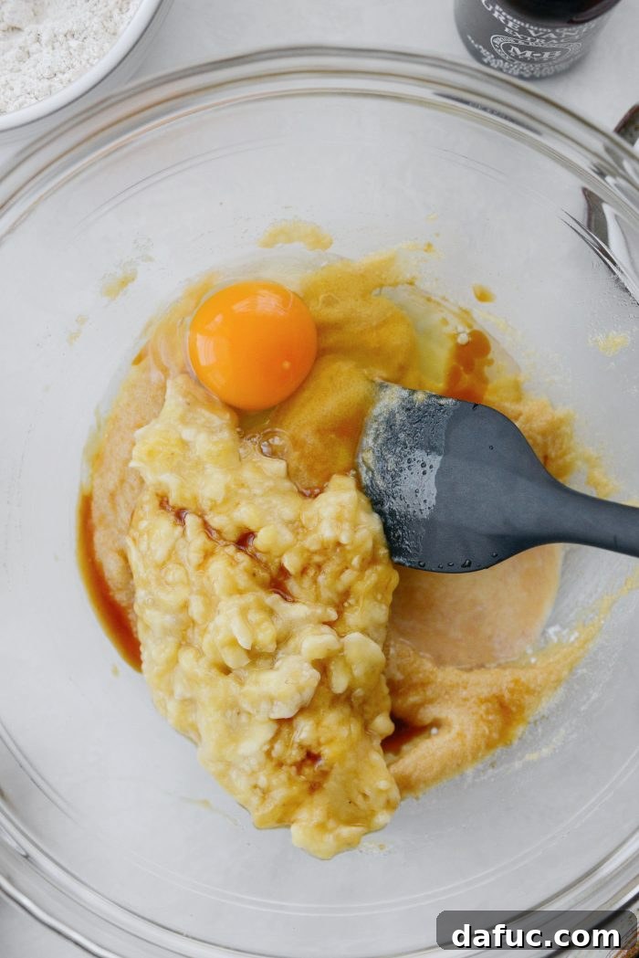 Mashed banana, egg, and vanilla extract added to the butter and sugar mixture