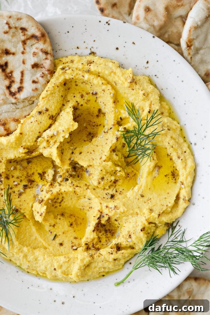 Golden Beet Hummus, a vibrant yellow dip in a bowl garnished with olive oil and za'atar