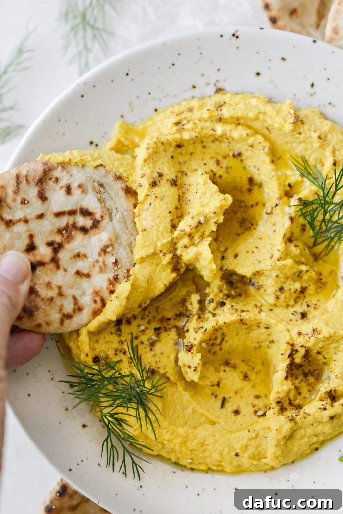 Close-up of Golden Beet Hummus with a fork taking a scoop, highlighting its creamy texture