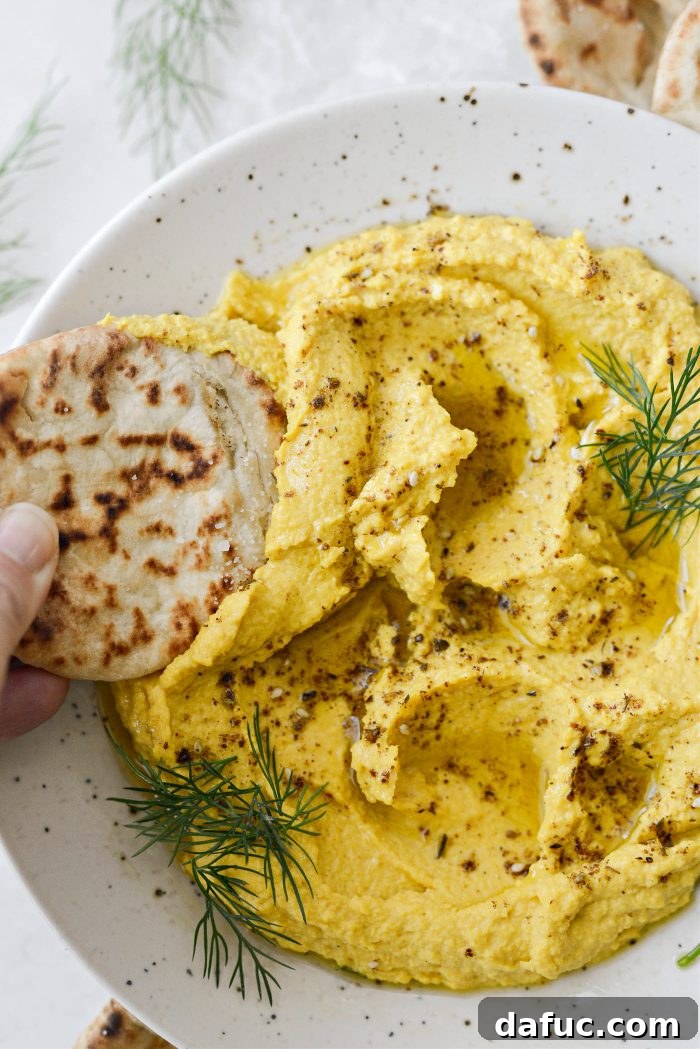 Golden Beet Hummus in a bowl with a slice of pita bread, ready for dipping