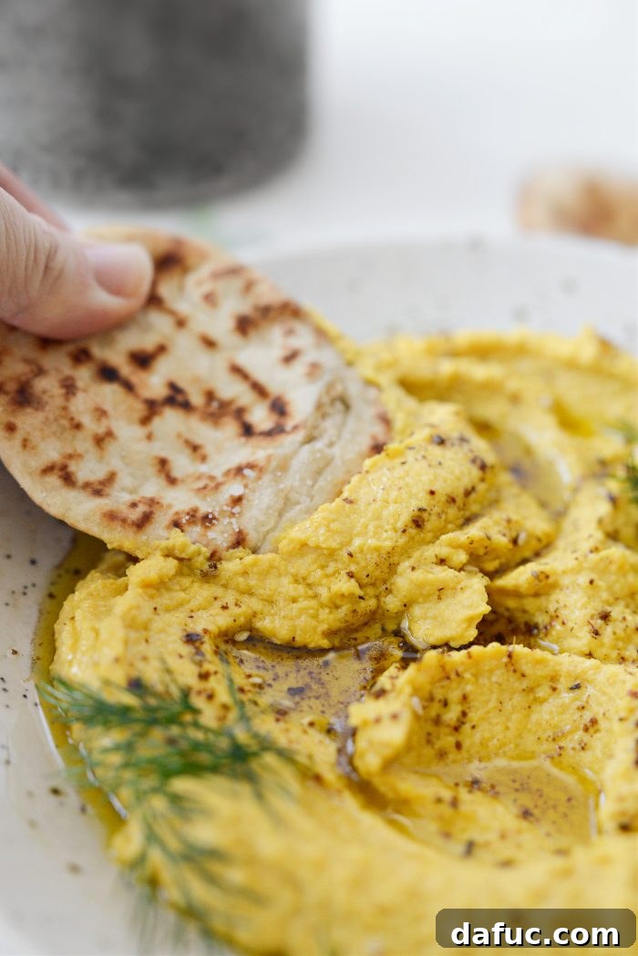 Close-up of Golden Beet Hummus showing its smooth texture and yellow color, with a spoon making a swirl