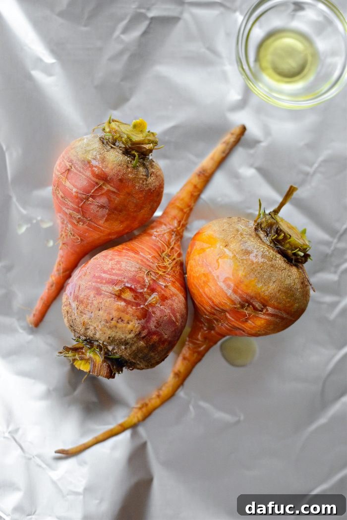 Golden beets drizzled with olive oil on a sheet of foil, ready for roasting