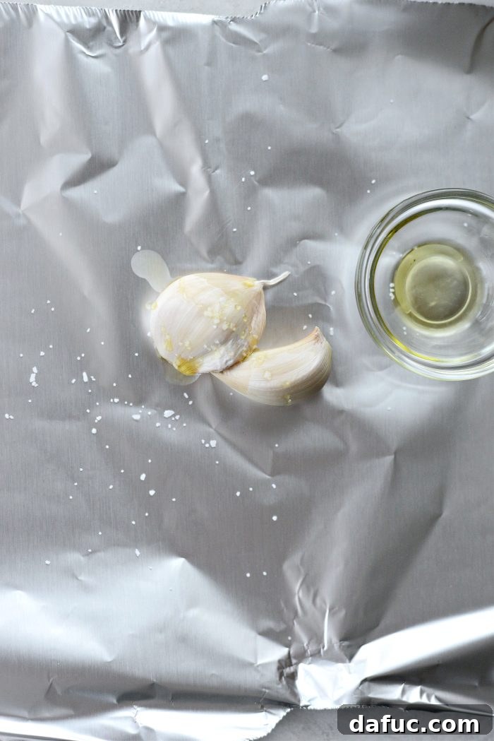 Unpeeled garlic cloves with olive oil and salt on a separate foil sheet