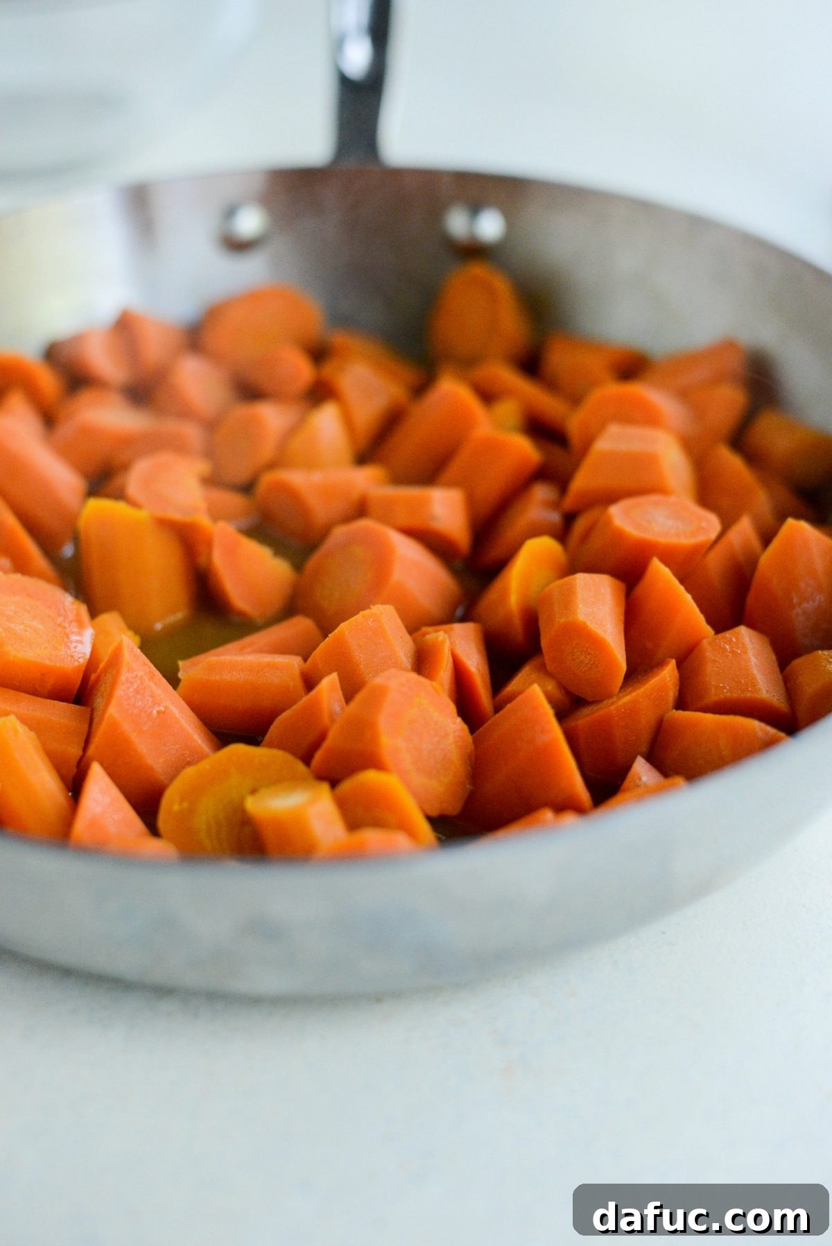 Caramelized Brown Sugar Carrots 7 A fork testing the tenderness of cooked carrots before the glaze fully thickens