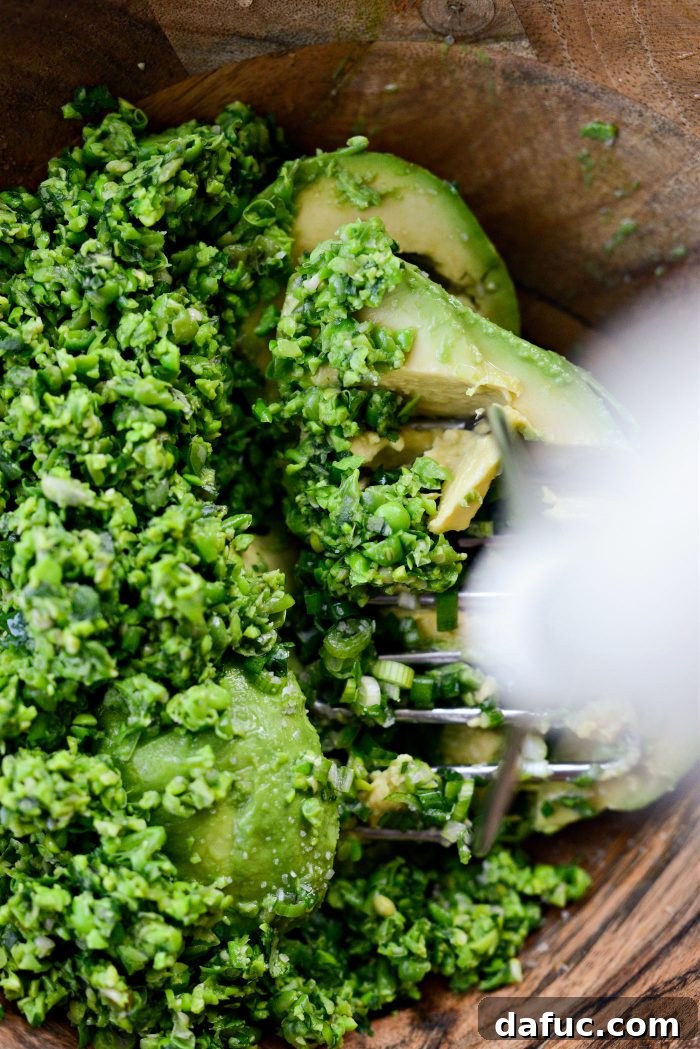 Vibrant Serrano Sweet Pea Guacamole 12 Mashing ingredients for Serrano Sweet Pea Guacamole with a potato masher