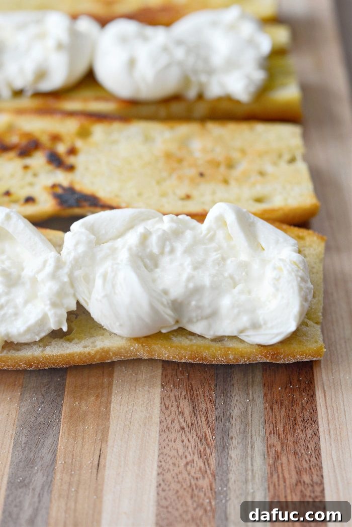 Spreading creamy burrata onto the toasted baguette halves