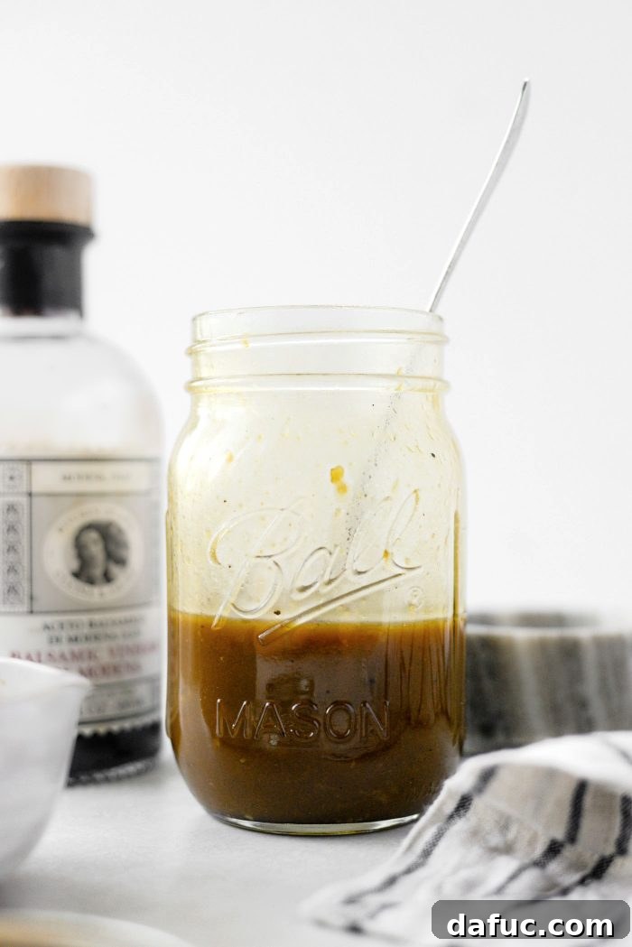 Delicious Balsamic Honey Dijon Vinaigrette in a glass jar with fresh herbs, ready for use