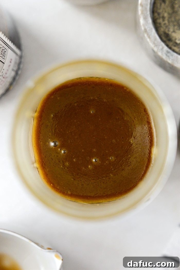 Zesty Honey Balsamic Dijon Vinaigrette 3 A close-up shot of Balsamic Honey Dijon Vinaigrette drizzled over fresh greens, showcasing its rich texture and appealing color.