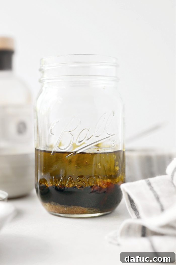 Zesty Honey Balsamic Dijon Vinaigrette 5 Hands measuring and adding ingredients into a glass jar, the initial step for making Balsamic Honey Dijon Vinaigrette.