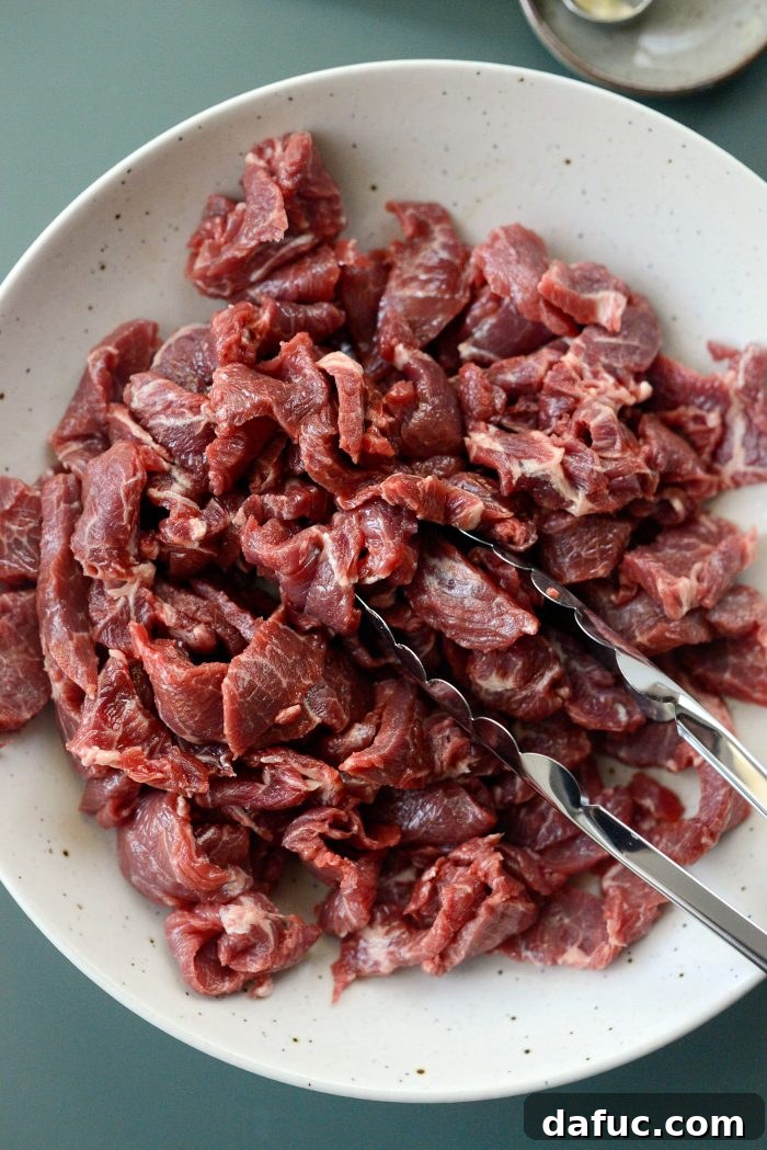 Sheet Pan Steak and Broccoli 8 Thinly sliced steak being tossed with toasted sesame oil in a bowl