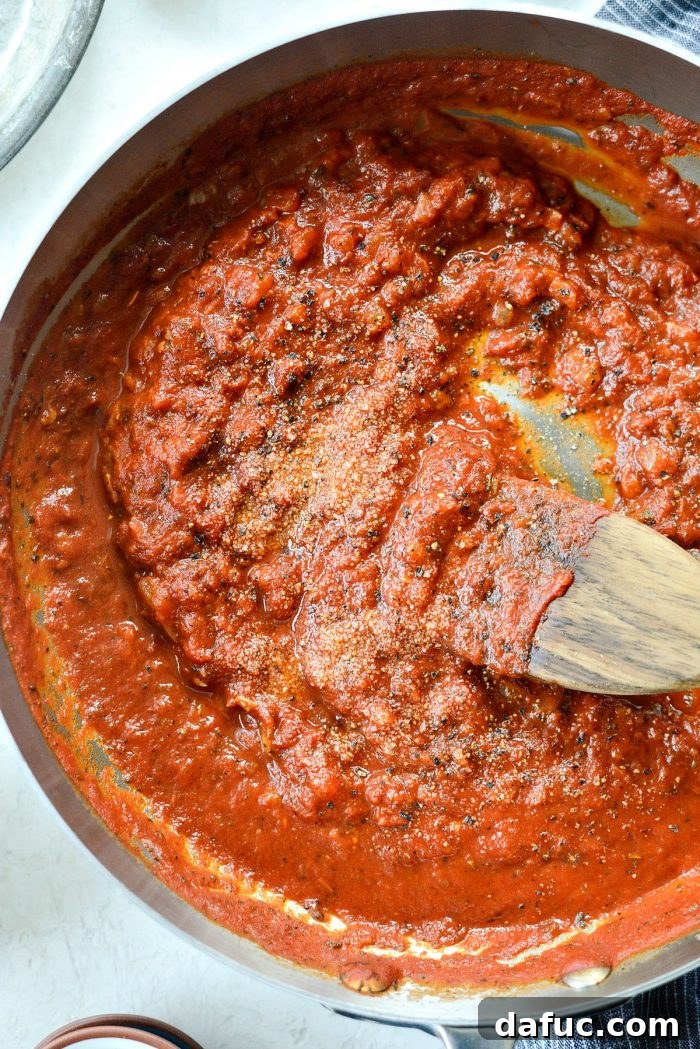 Perfect Homemade Pizza Sauce 13 The homemade pizza sauce simmering gently in the skillet, its texture becoming thick and robust.