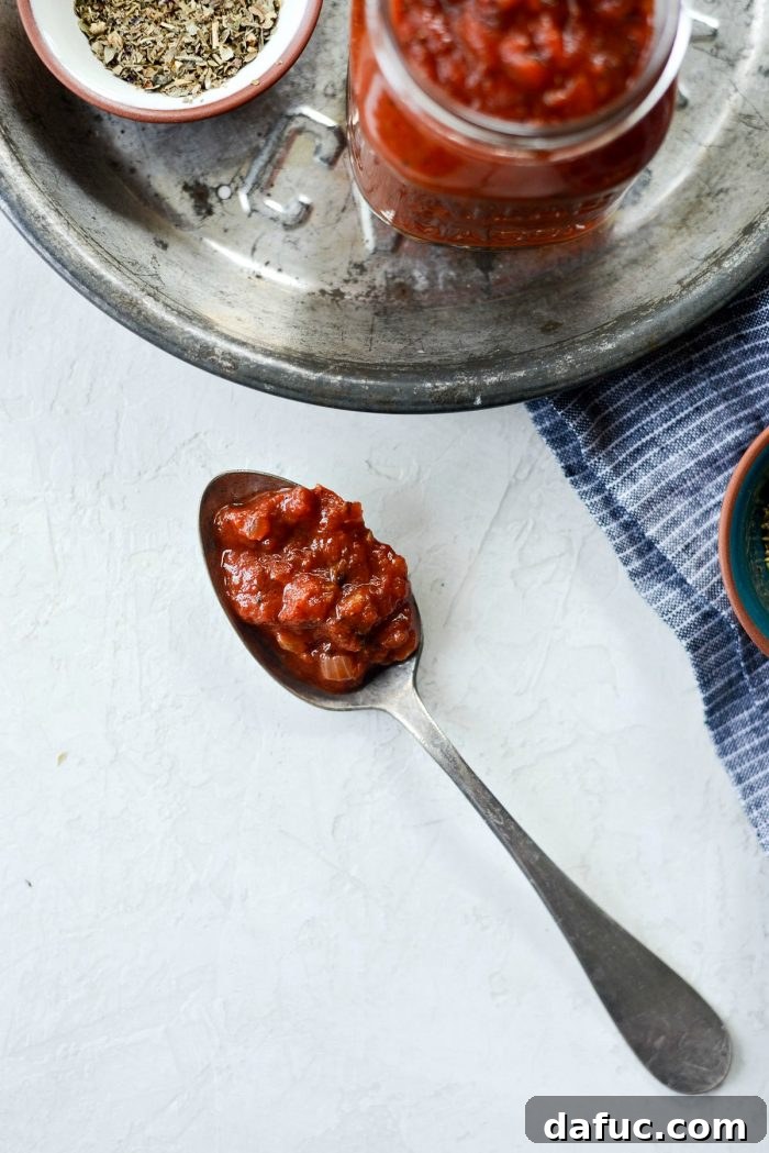 Perfect Homemade Pizza Sauce 19 A scoop of rich, vibrant homemade pizza sauce captured on a spoon, ready to be spread on a crust, highlighting its inviting texture.