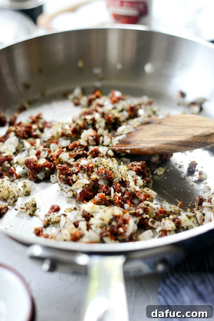 Perfect Homemade Pizza Sauce 8 The mixture of onions, garlic, sun-dried tomatoes, and herbs being stirred gently in the skillet.