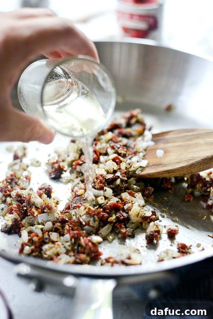 Perfect Homemade Pizza Sauce 9 White wine being poured into the skillet with sautéed ingredients, creating steam as it deglazes the pan.