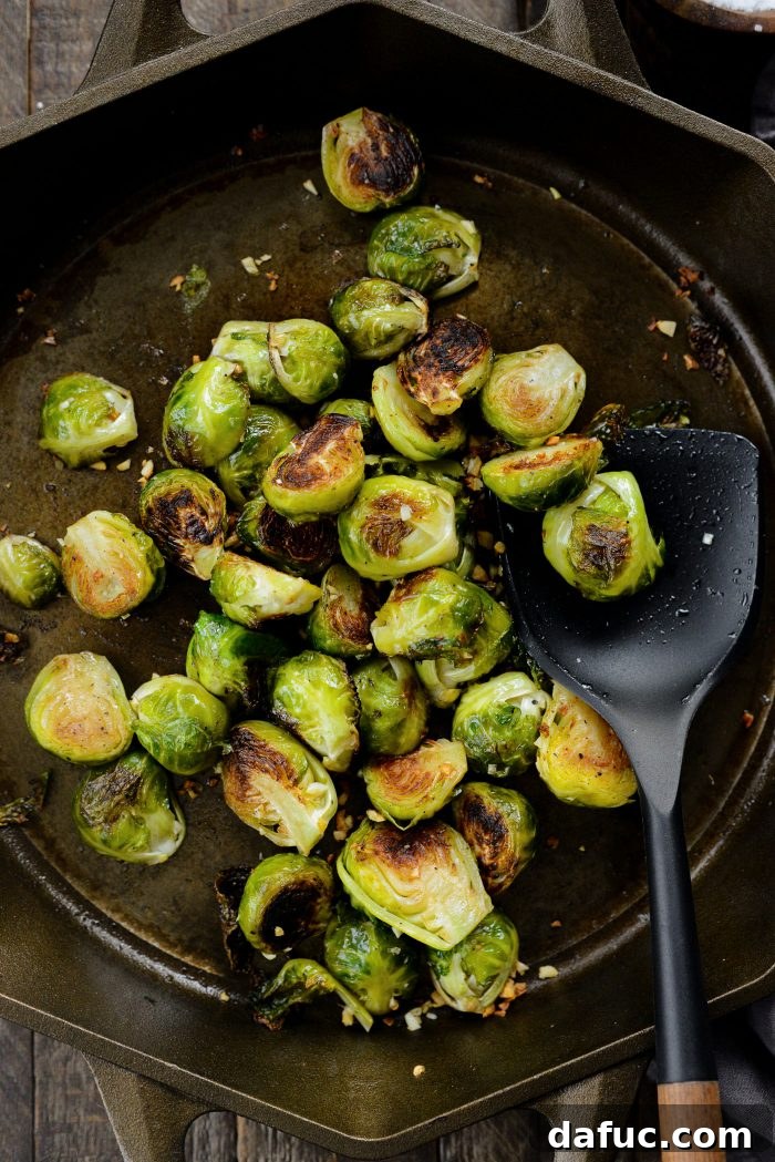 Brussels sprouts being tossed in a skillet during oven roasting to ensure even cooking