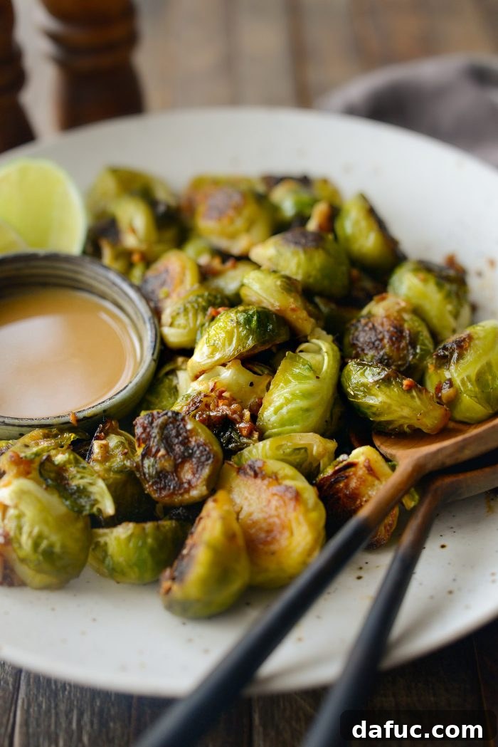 Stack of Miso Glazed Roasted Brussels Sprouts on a plate with a lime wedge