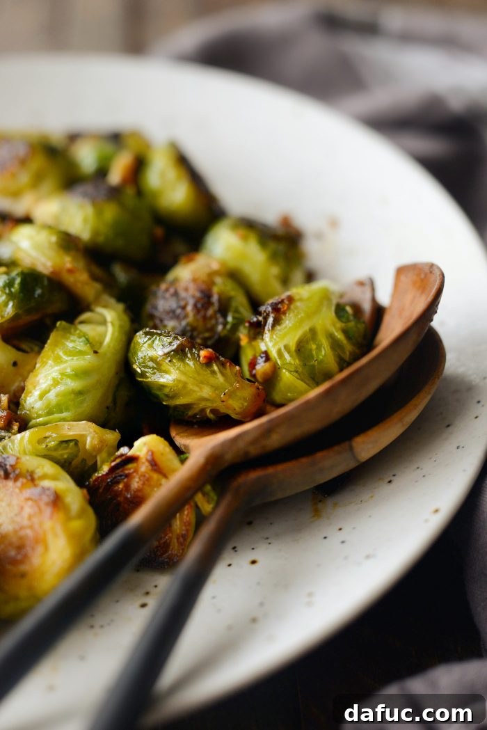 Final presentation of Miso Glazed Roasted Brussels Sprouts in a serving dish, garnished with fresh lime
