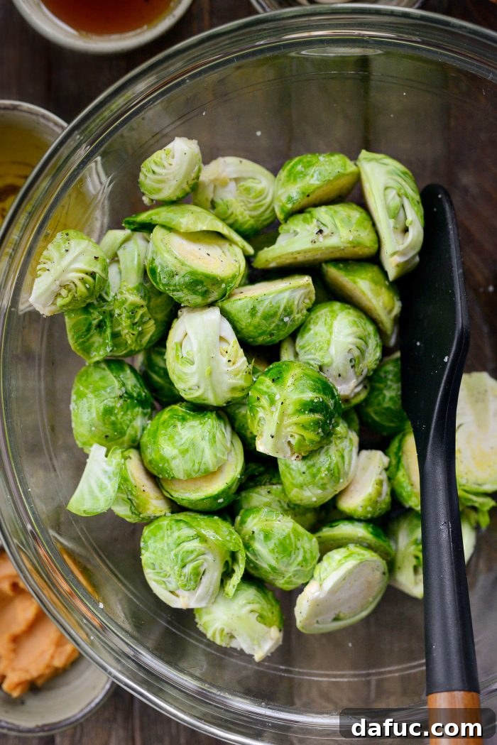 Hands tossing Brussels sprouts in a bowl to coat them evenly with seasoning