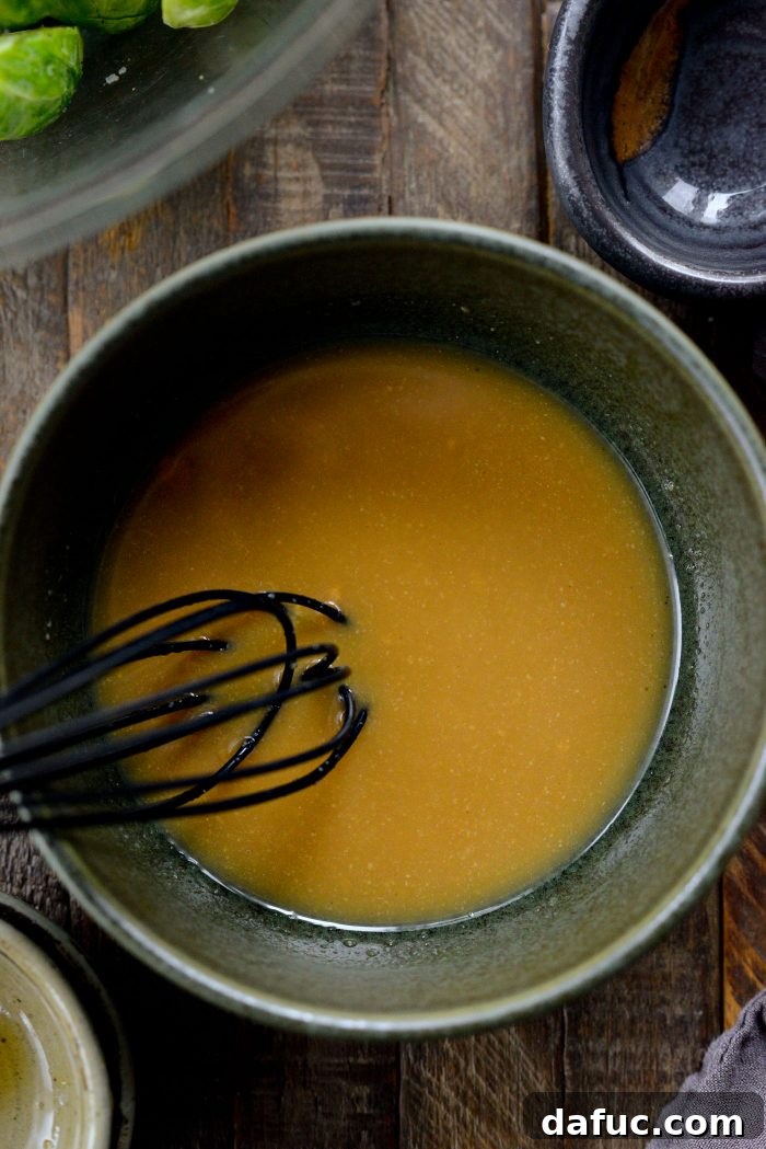 Small bowl with miso paste, rice vinegar, and maple syrup being whisked to form a glaze