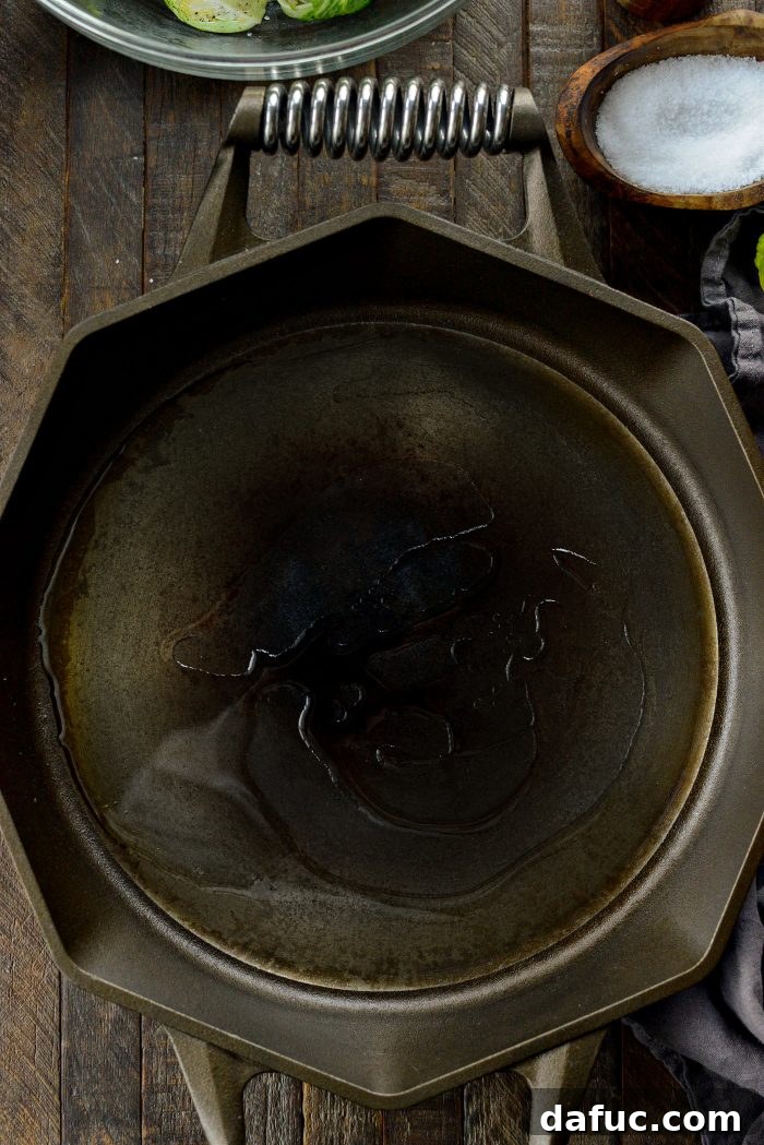 Avocado oil heating in a large cast iron skillet on a stovetop