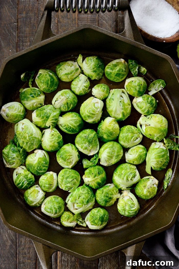 Halved Brussels sprouts arranged cut-side down in a single layer in a hot cast iron skillet