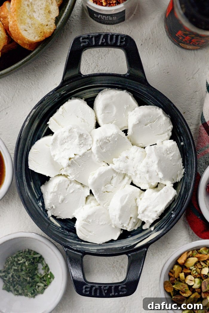 Chili Honeyed Chèvre Indulgence 6 Slicing an 8-ounce goat cheese log into coins and arranging them in a buttered baking dish.