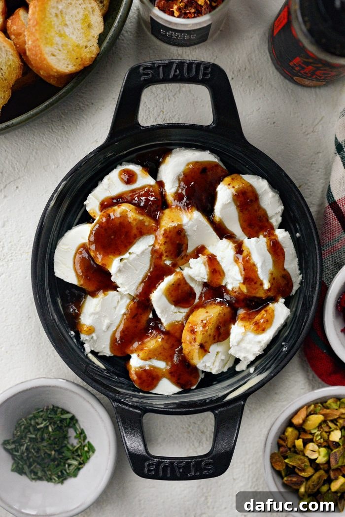 Chili Honeyed Chèvre Indulgence 7 Drizzling fig jam generously over the arranged goat cheese in the baking dish.