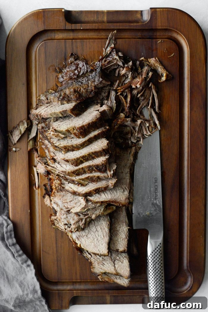 Sweet Onion Braised Beef 20 Slicing or shredding the tender pot roast on a cutting board.