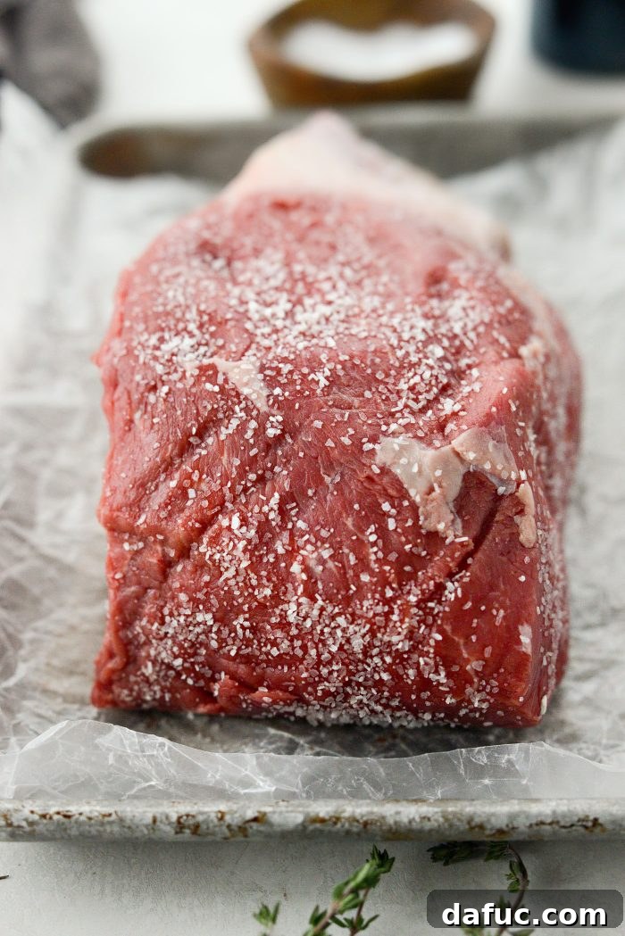 Sweet Onion Braised Beef 5 Seasoning a beef chuck roast generously with kosher salt on a cutting board.