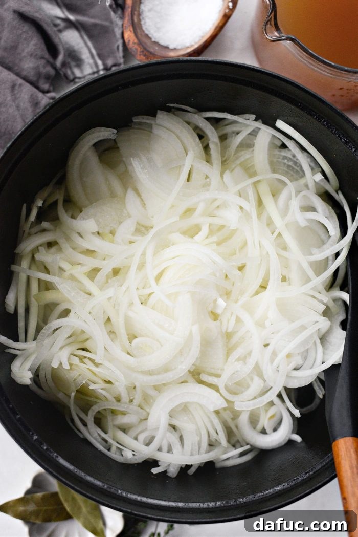 Sweet Onion Braised Beef 10 Adding sliced yellow onions and salt to melted butter in the Dutch oven.