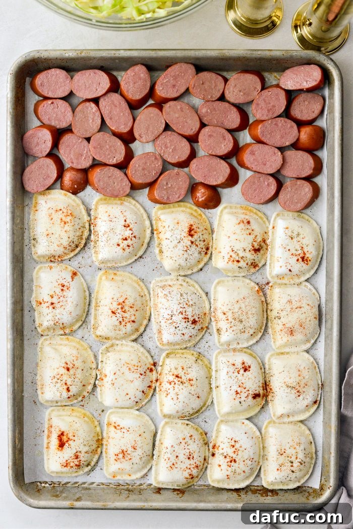 Arranging sliced kielbasa and frozen pierogies on the large sheet pan