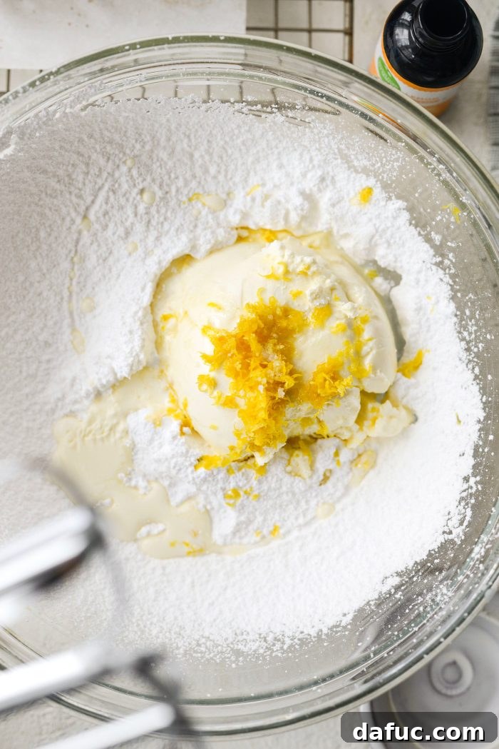 Ingredients for lemon mascarpone frosting including powdered sugar, mascarpone cheese, lemon zest, and heavy cream in a bowl