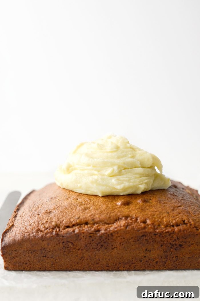 Lemon mascarpone frosting being spread over a cooled Lemon Pistachio Cake with an offset spatula