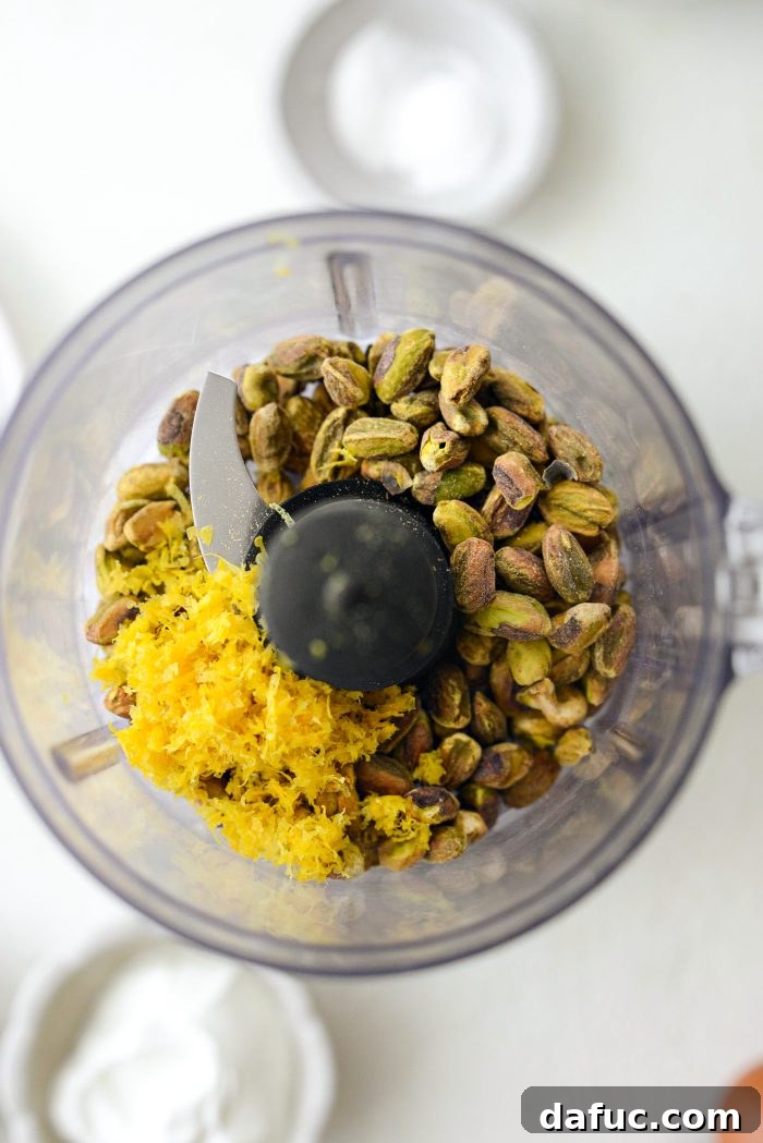Unsalted pistachios and fresh lemon zest in a mini food processor bowl