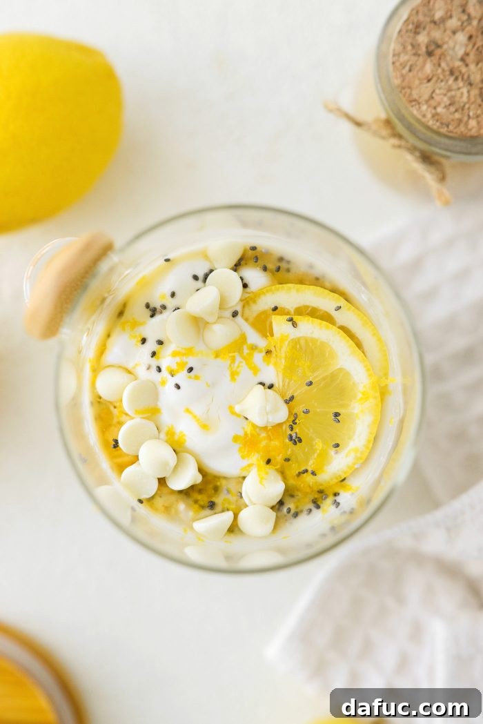 Lemon Cheesecake Overnight Oats topped with yogurt, maple syrup, lemon zest, and white chocolate chips