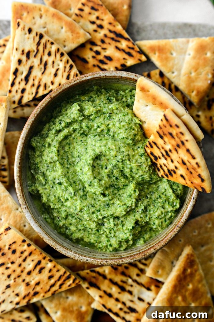 Creamy Artichoke Arugula Dip 12 A close-up of the Artichoke Arugula Dip being scooped with a piece of toasted pita.
