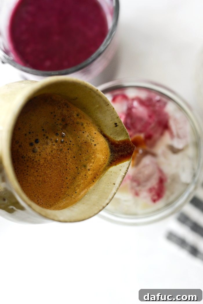Pouring espresso shot into iced blueberry latte