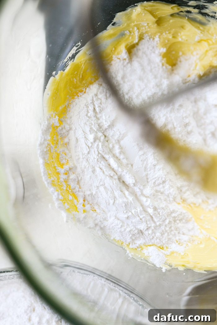 Gradually adding sifted powdered sugar to buttercream