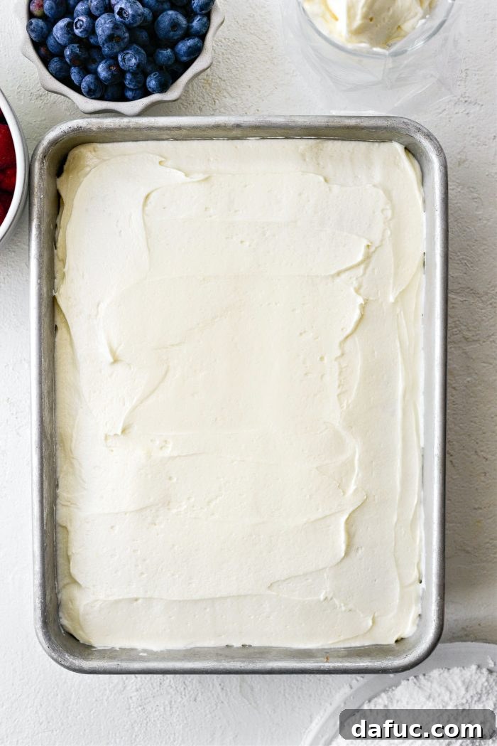 Using an offset spatula to spread buttercream smoothly on the cake.