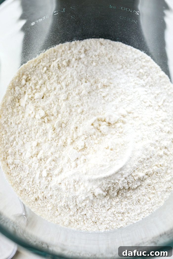Adding homemade white cake mix to the bowl of a stand mixer.