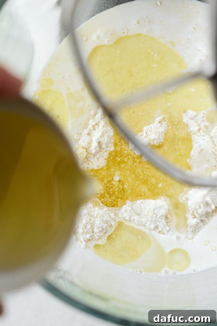Pouring neutral oil into the cake mix in the mixer bowl.
