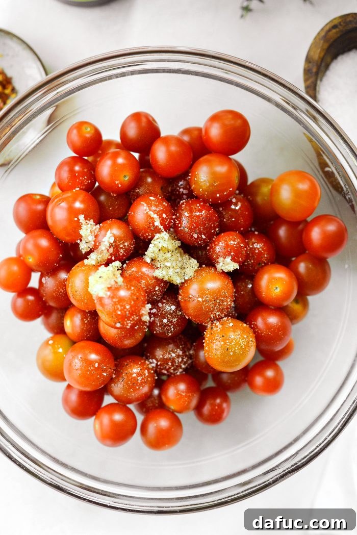 Sweet Blistered Tomatoes, Creamy Burrata, Crispy Pancetta 11 Cherry tomatoes seasoned with olive oil, grated garlic, salt, and pepper in a bowl.