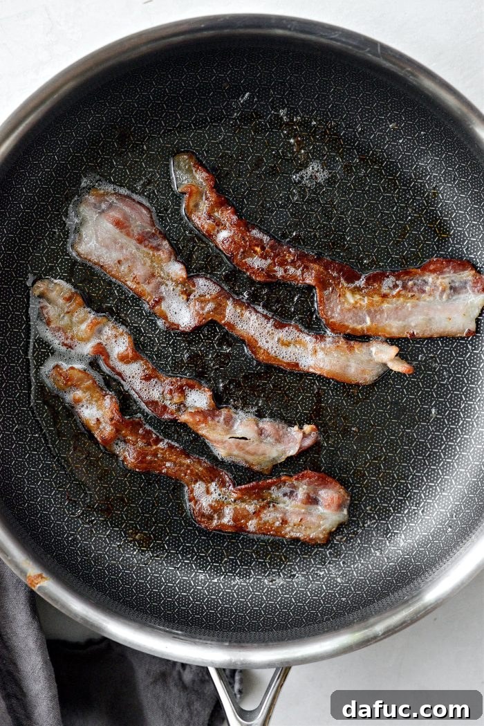 Ultimate Burger Bowl Creations 5 Cooking bacon in a skillet