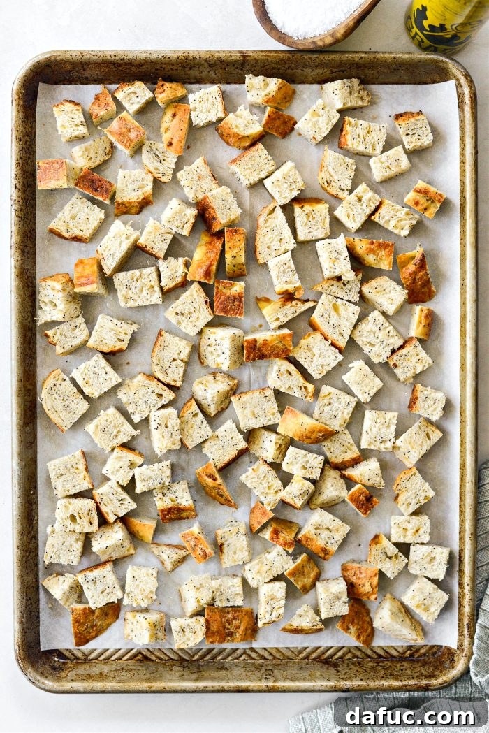 Golden Crispy Homemade Croutons 6 Cubed bread spread in a single layer on a baking sheet, sprayed with olive oil and seasoned with kosher salt